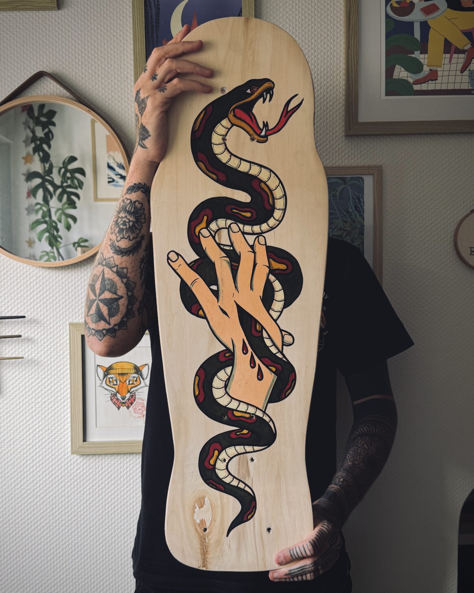 Planche de skateboard upcyclée peinte à la main représentant un serpent noir old school s'enroulant autour d'une main entaillée.